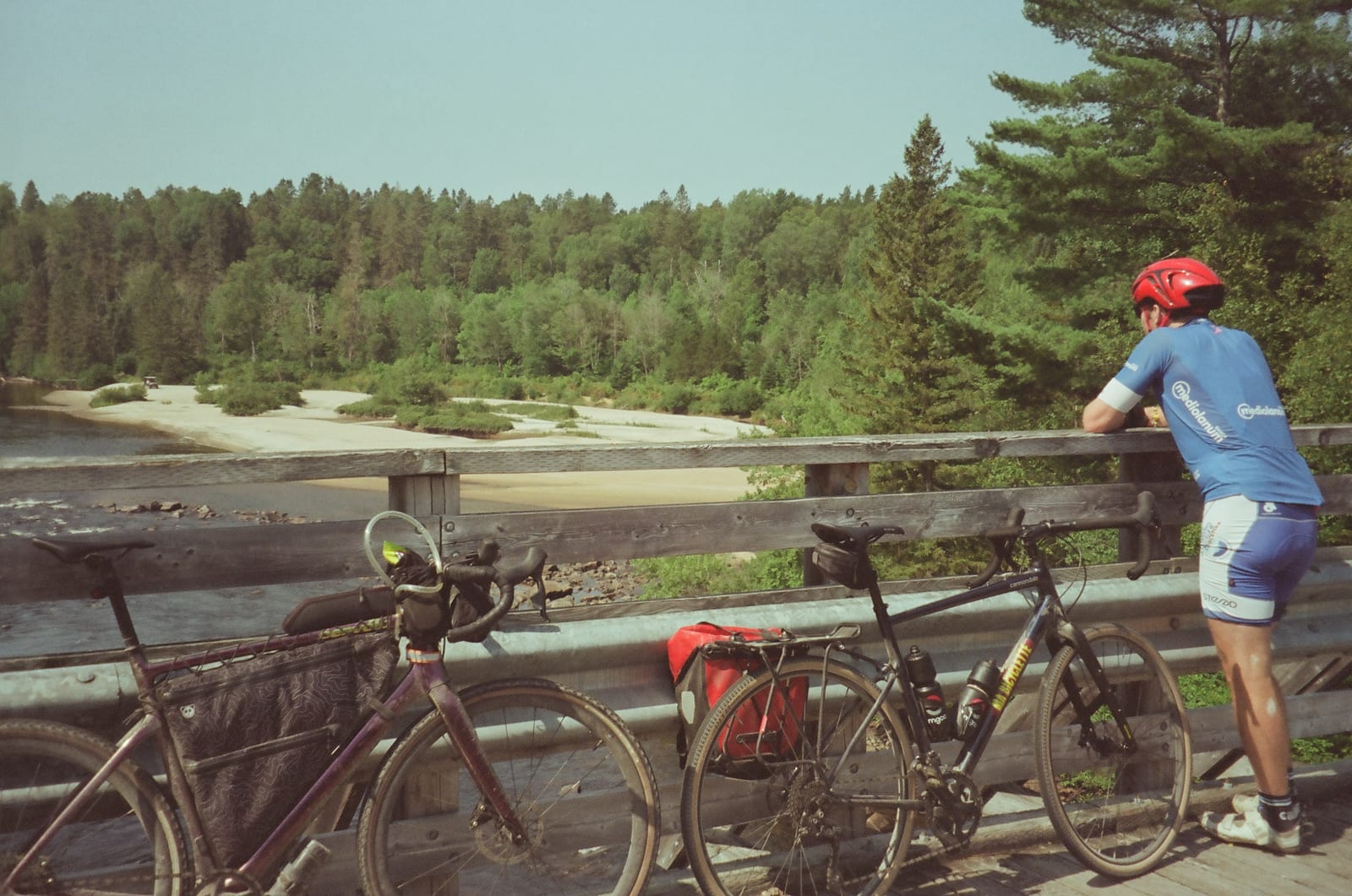 A cyclist crossing a long bridge beside two loaded touring bikes