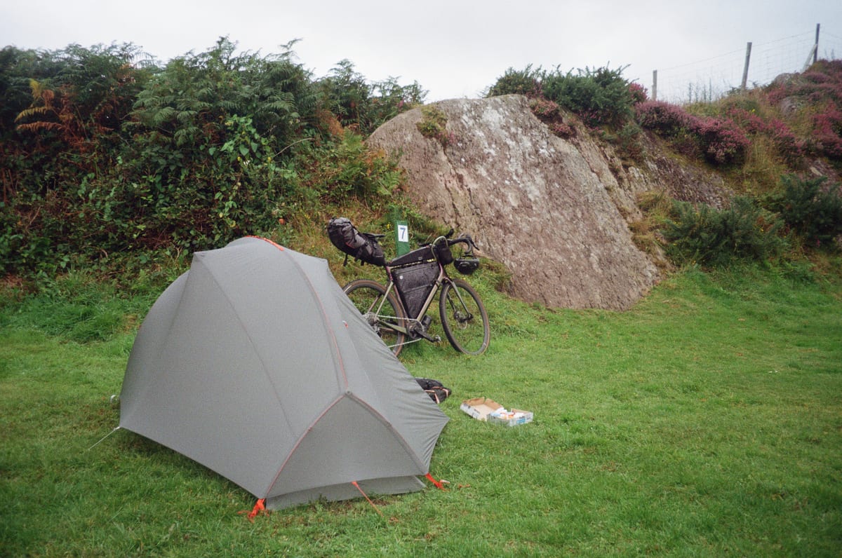 A touring bike beside a tent at a quiet campsite