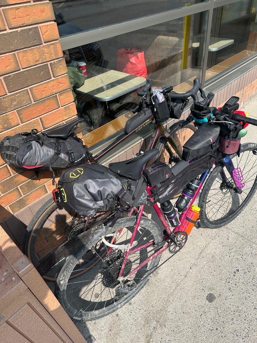 Loaded touring bikes parked together outside a small shop