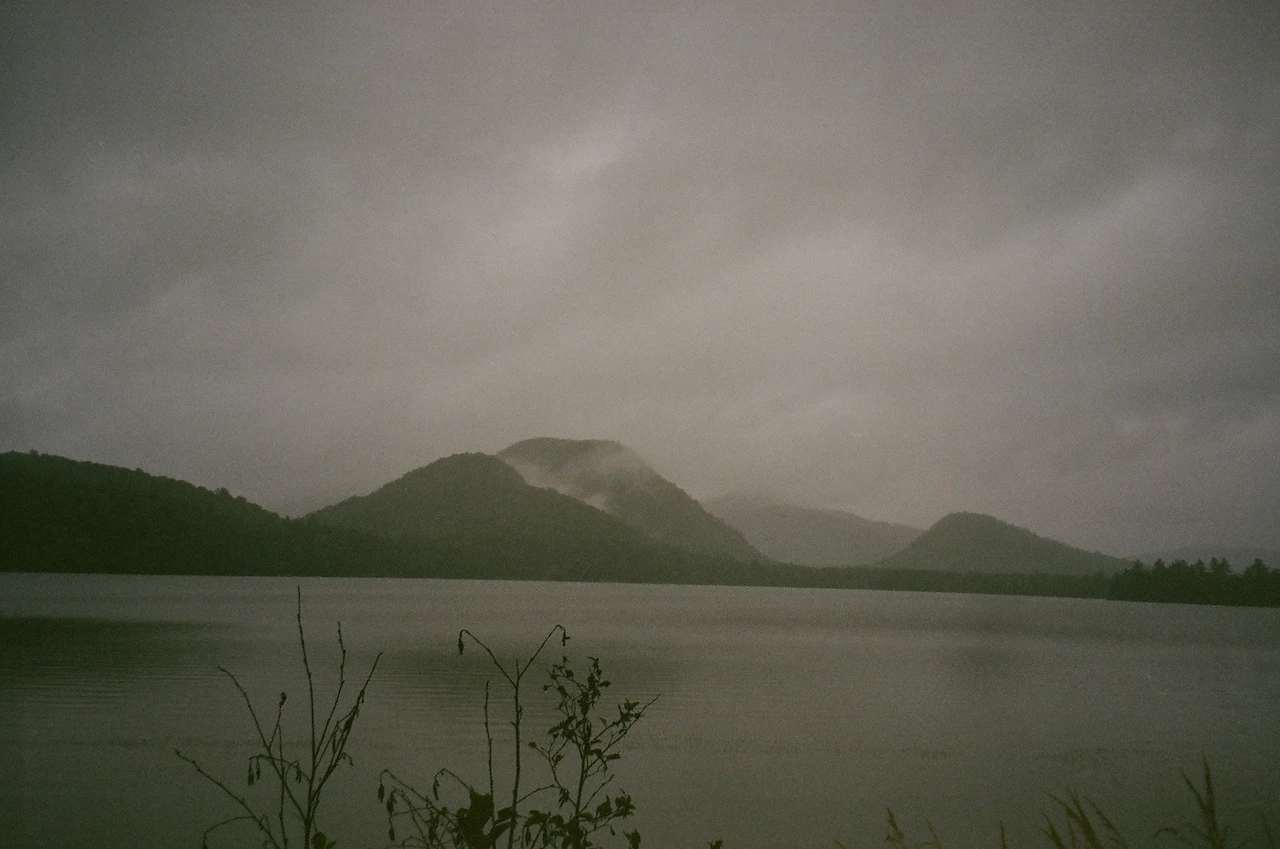 Low clouds settling over a dark lake and rounded mountain