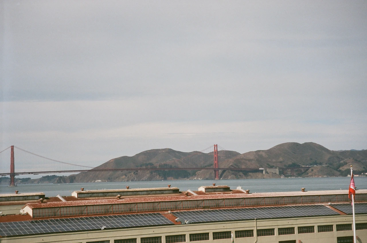 A long harbour wall crossing pale water toward distant hills