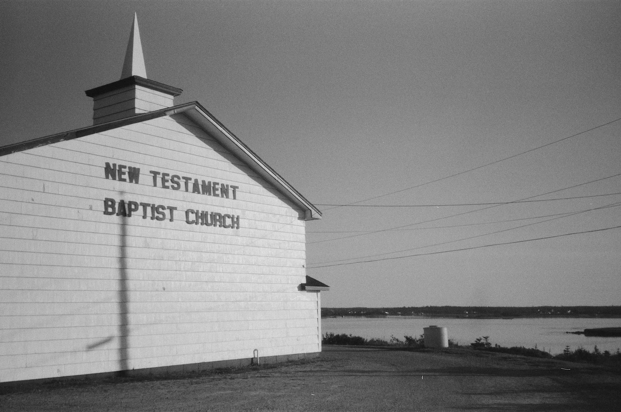A small white wooden building standing alone beneath an empty sky