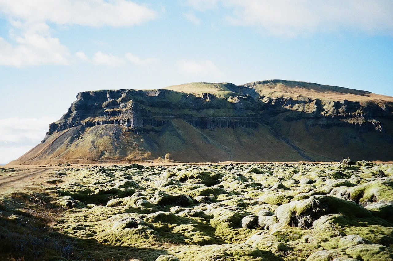A broad flat-topped mountain above a rocky green plain