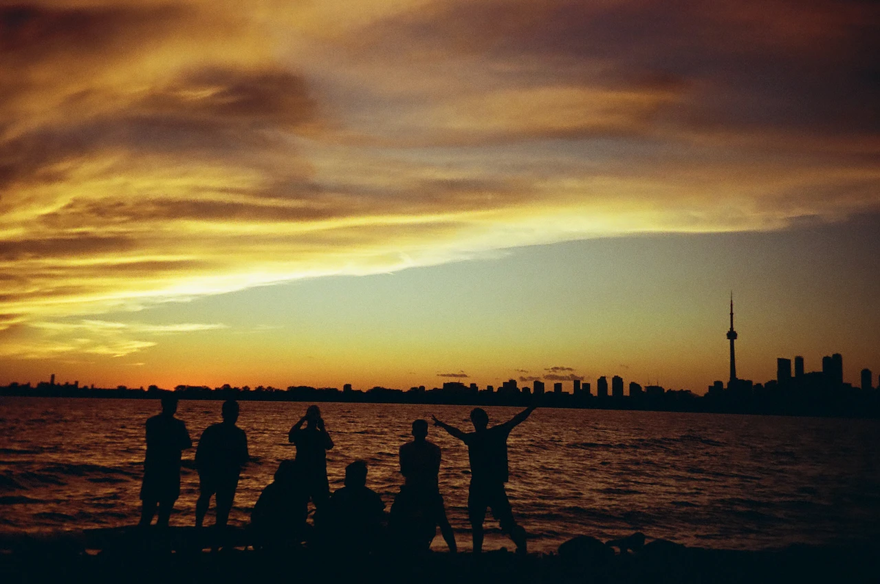 Anonymous silhouettes watching a vivid sunset across open water