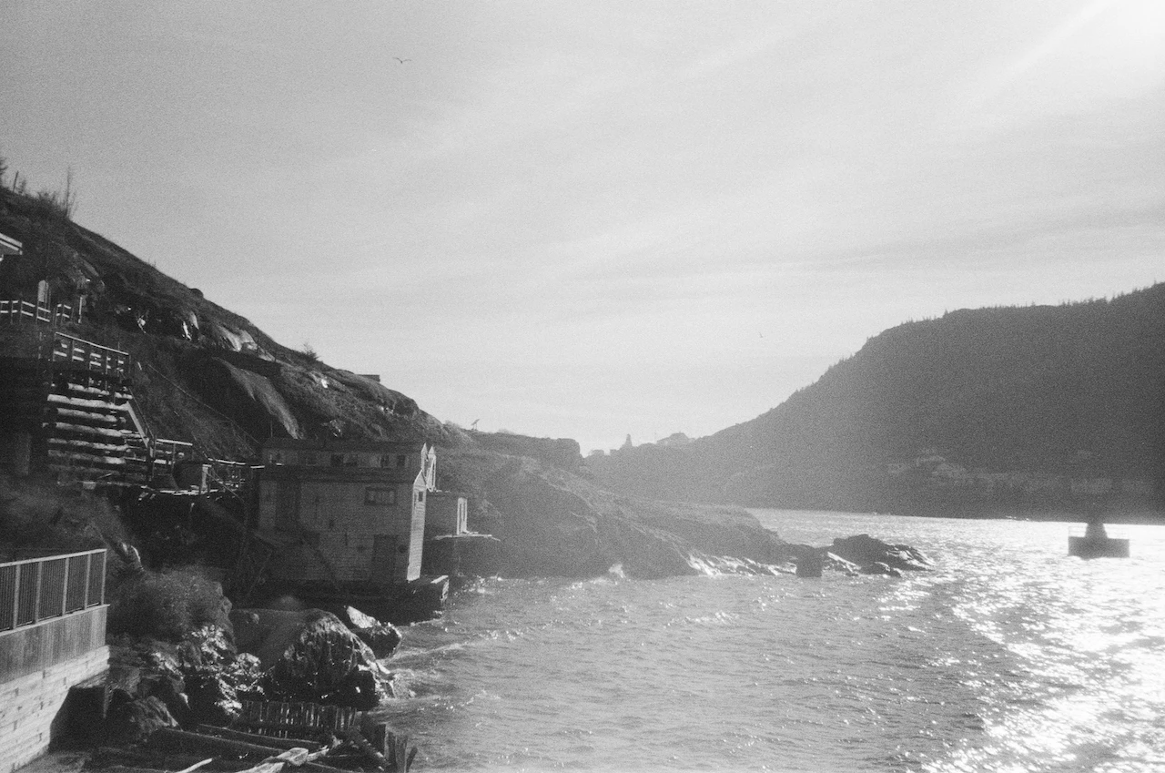 A monochrome coastal settlement built between steep rock and bright water