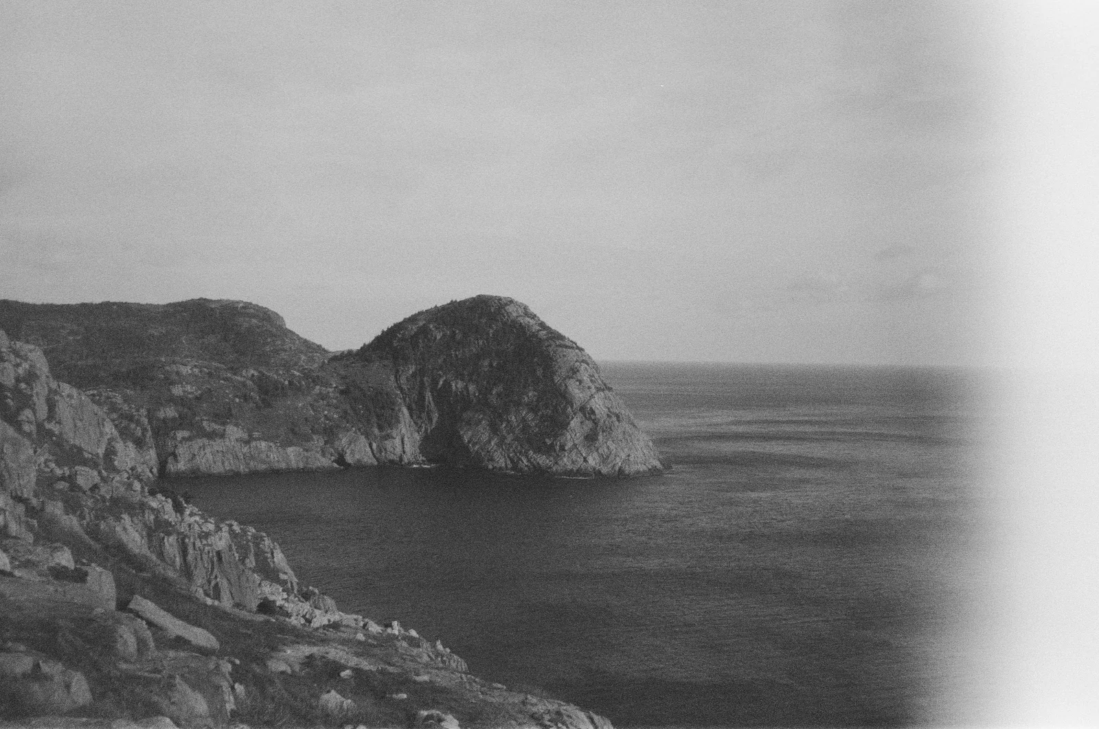 Monochrome rocky headlands receding into a calm sea