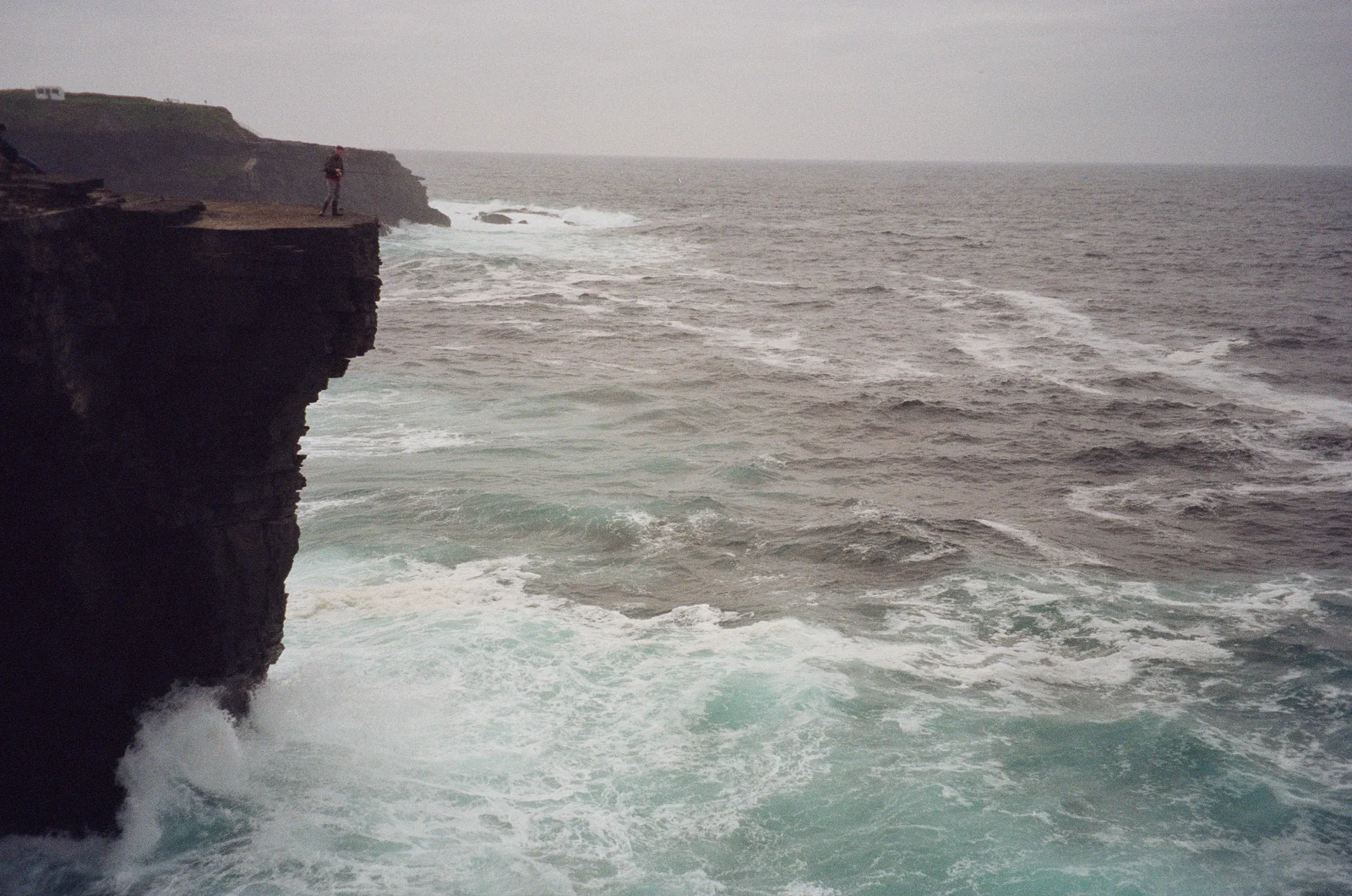 White waves striking the base of a dark sea cliff