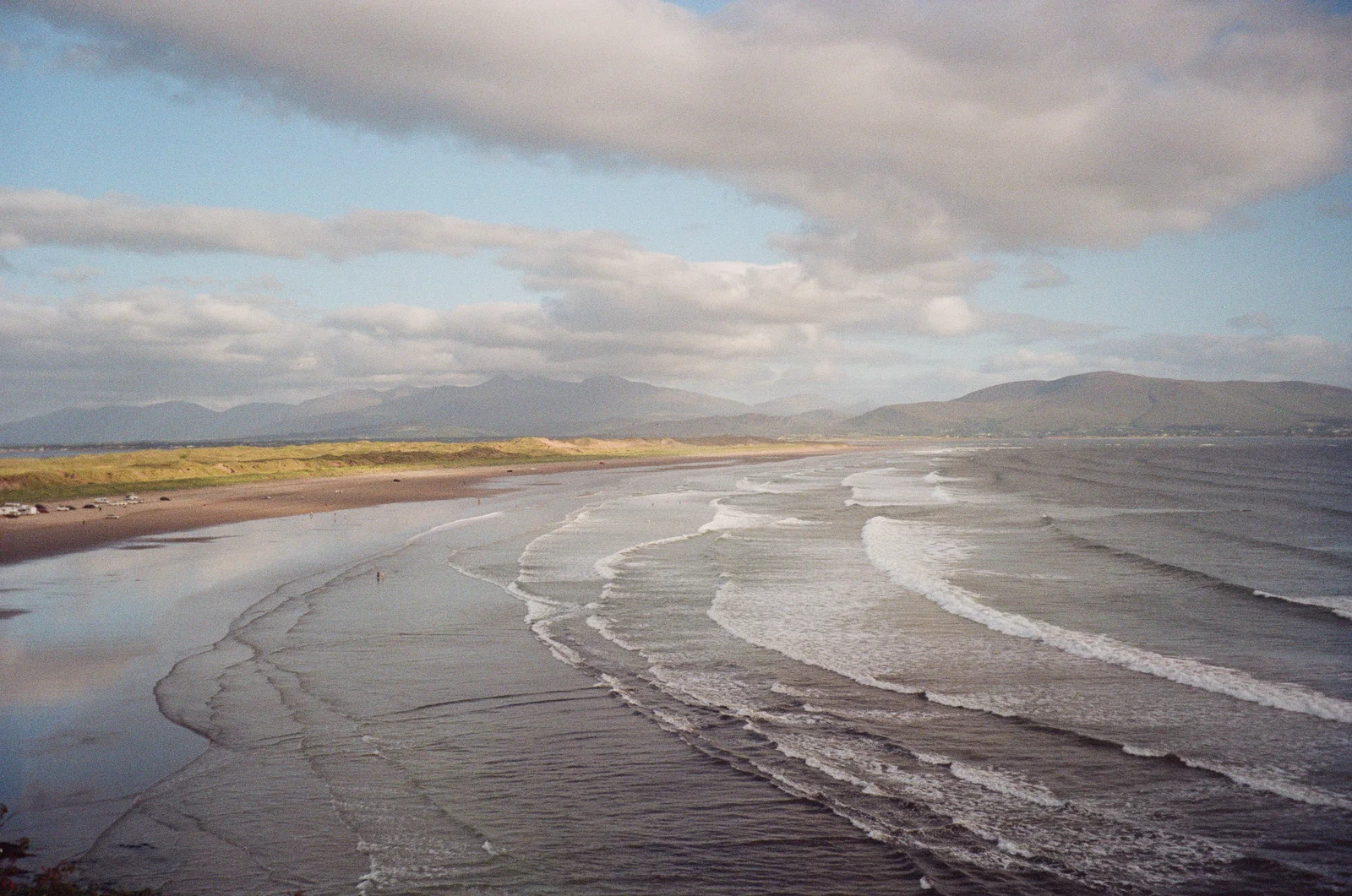 A wide empty beach stretching toward distant mountains