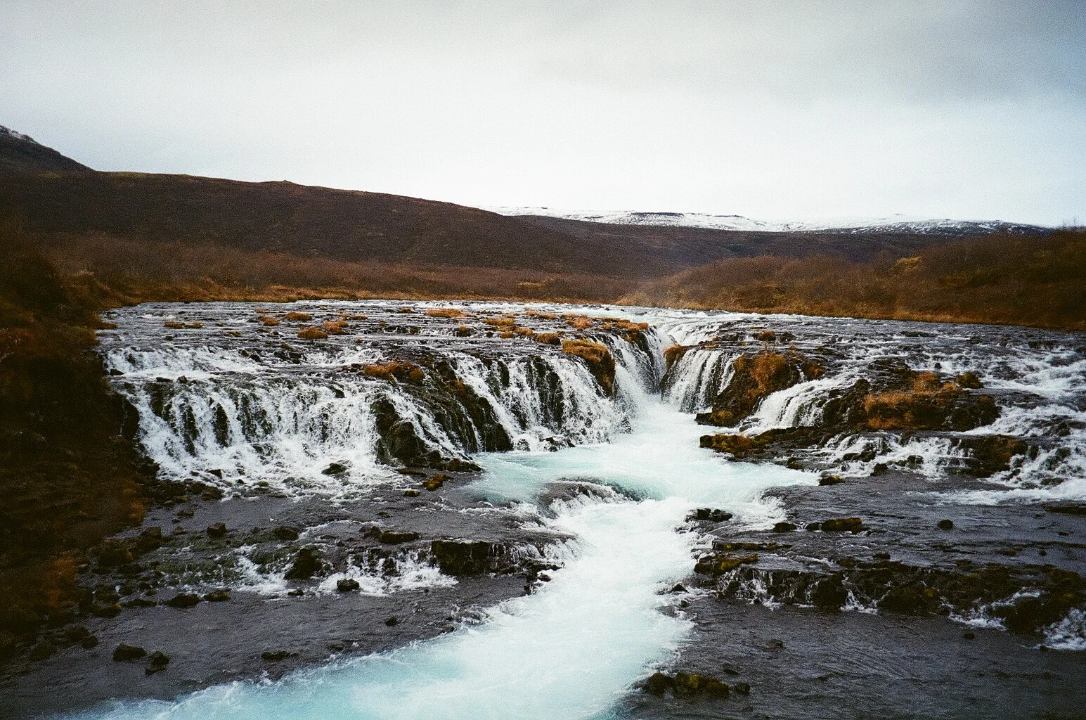 A stepped waterfall running across a dark volcanic plain