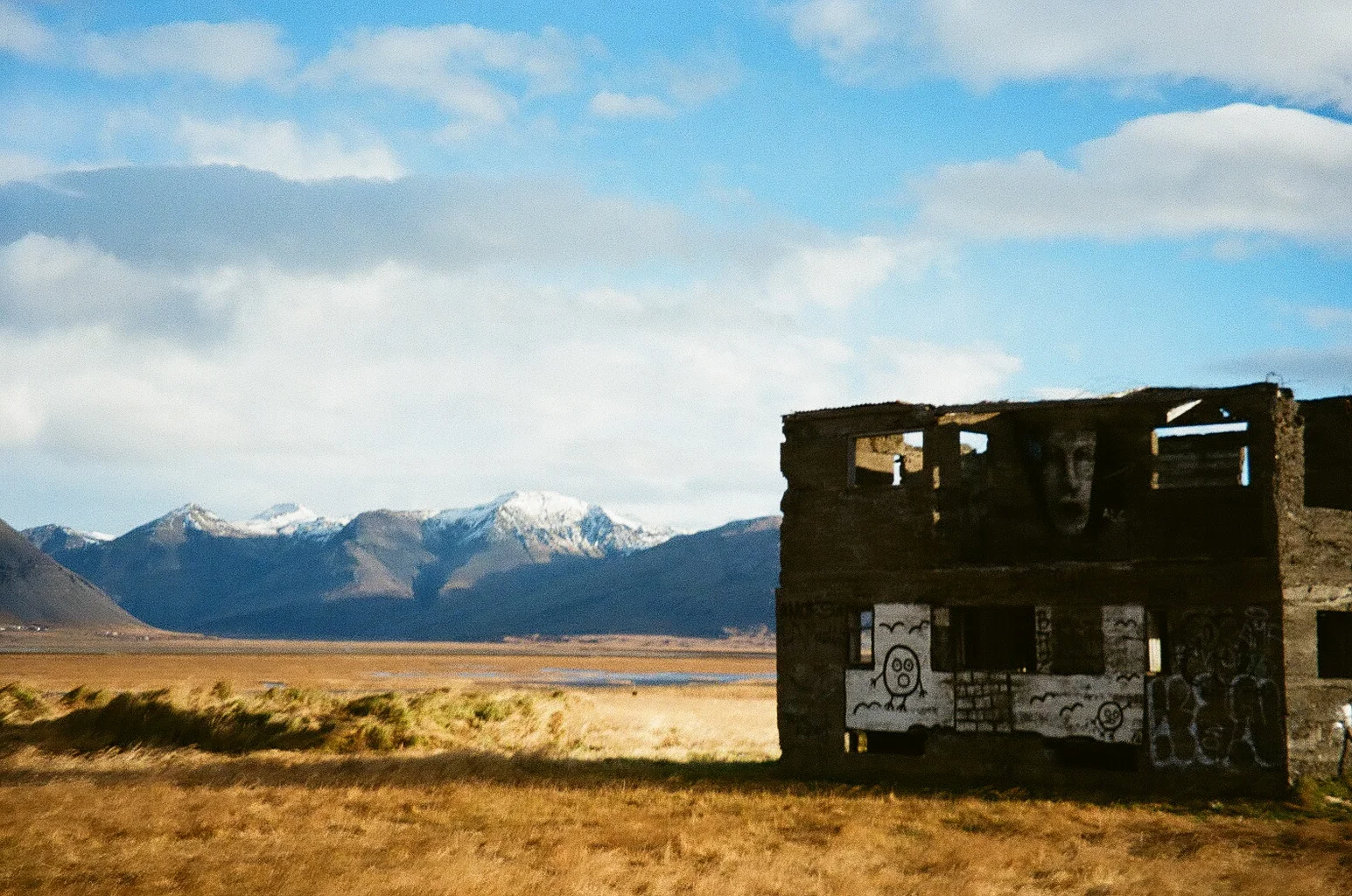 A weathered abandoned shelter standing before distant mountains