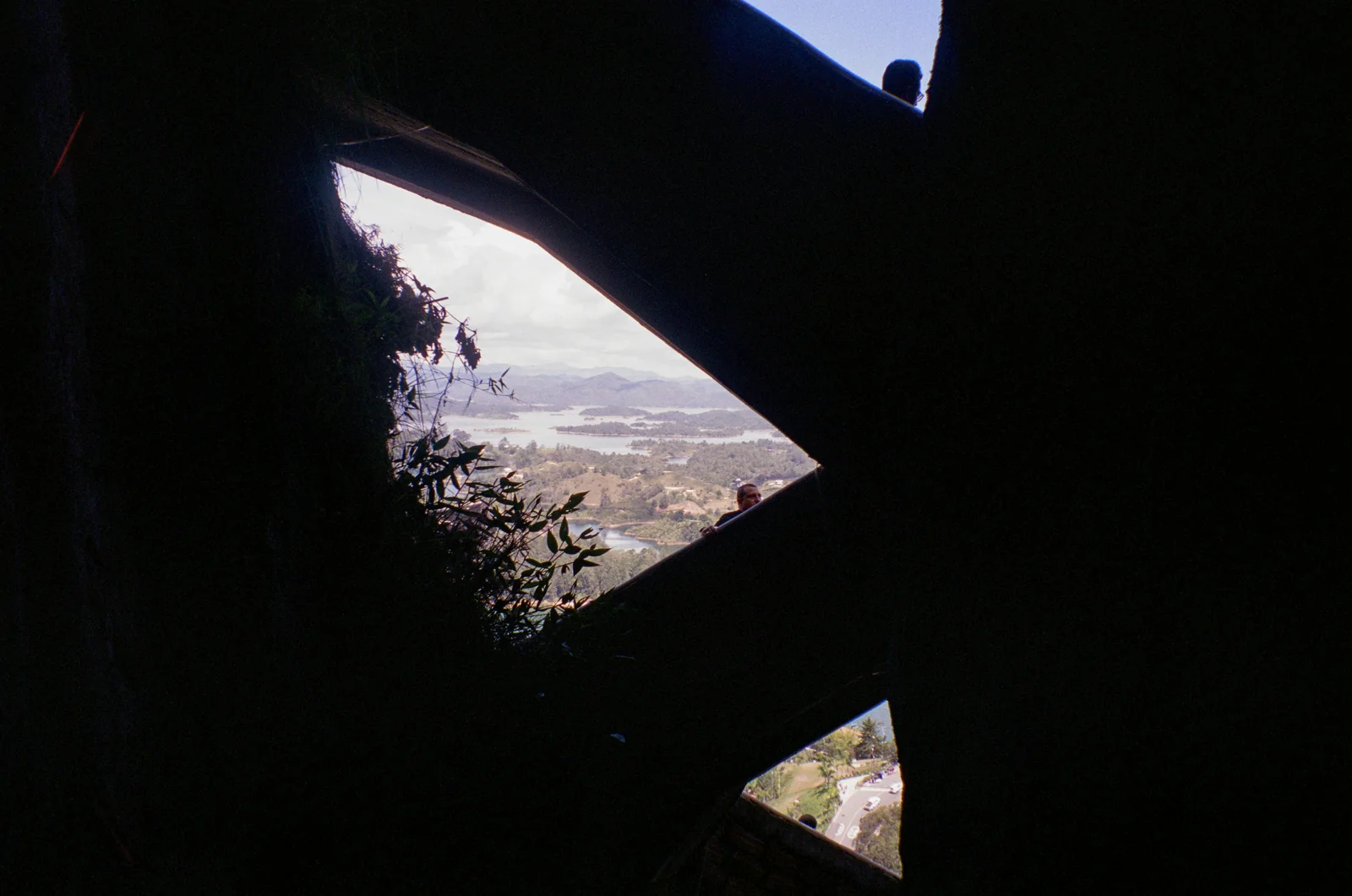 A dark angular window frame revealing a hillside city beyond