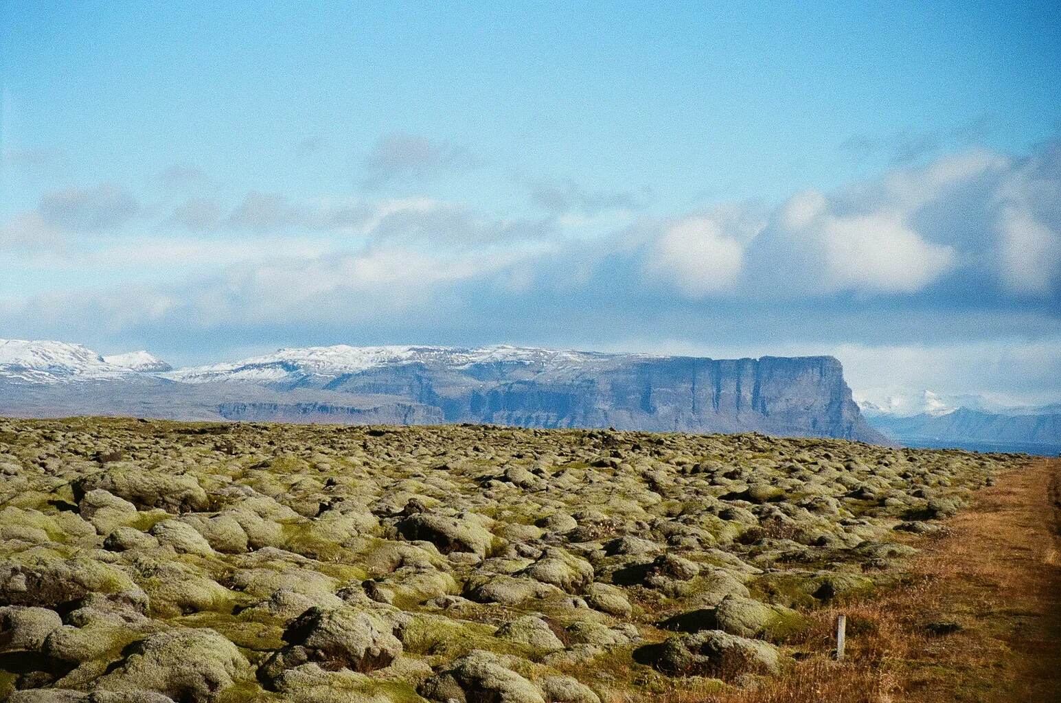A moss-covered lava field beneath a broad flat-topped mountain