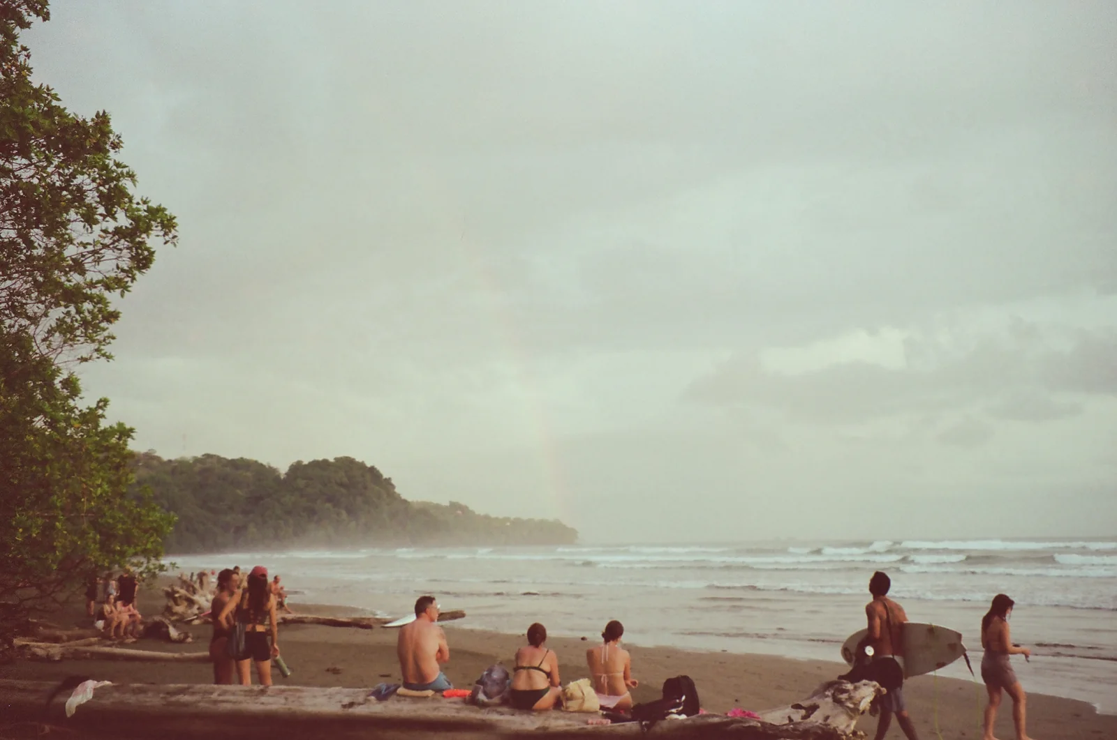 Anonymous beachgoers resting near the water beneath a pale sky