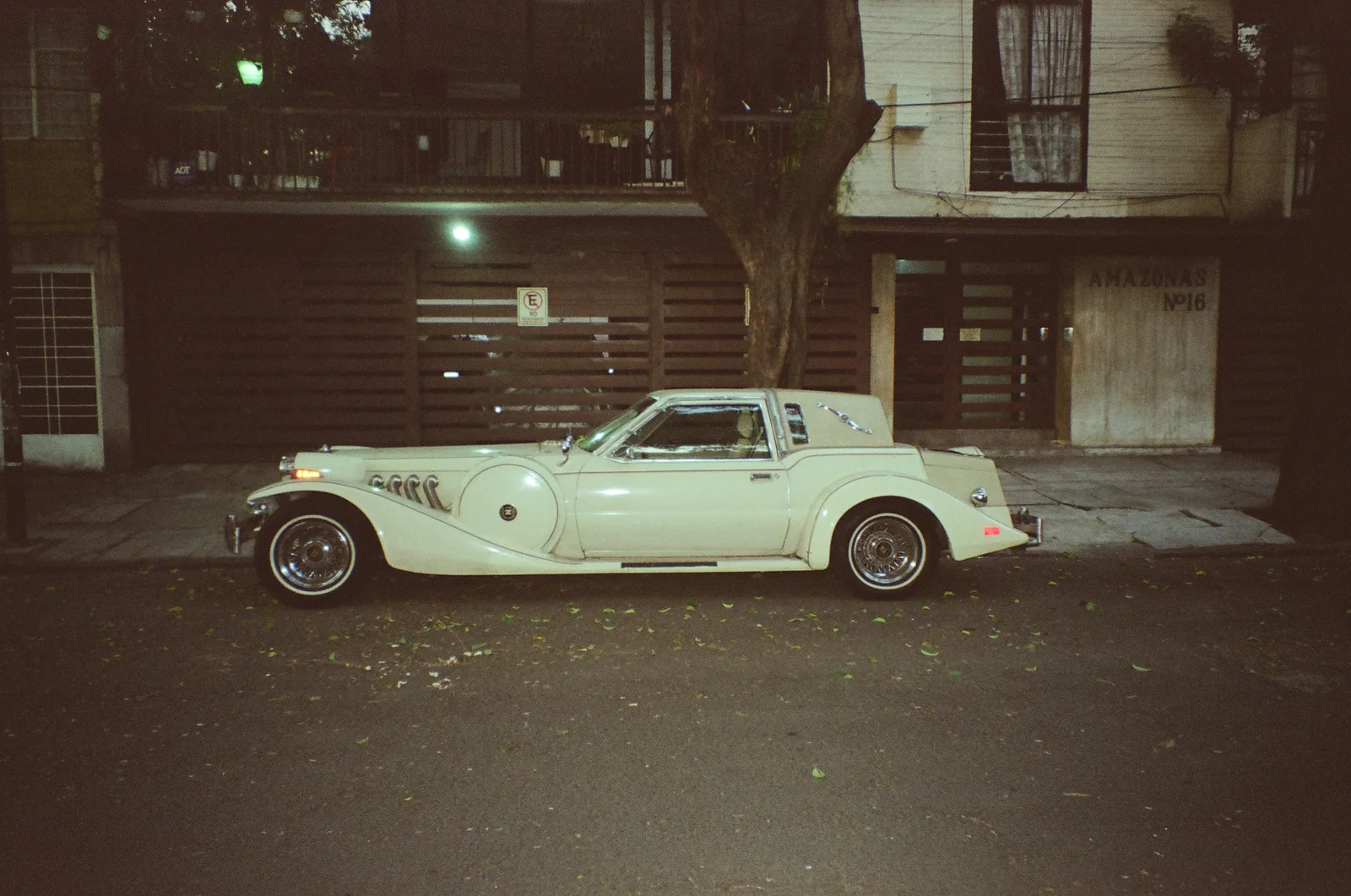 A white vintage car parked on a quiet city street at night